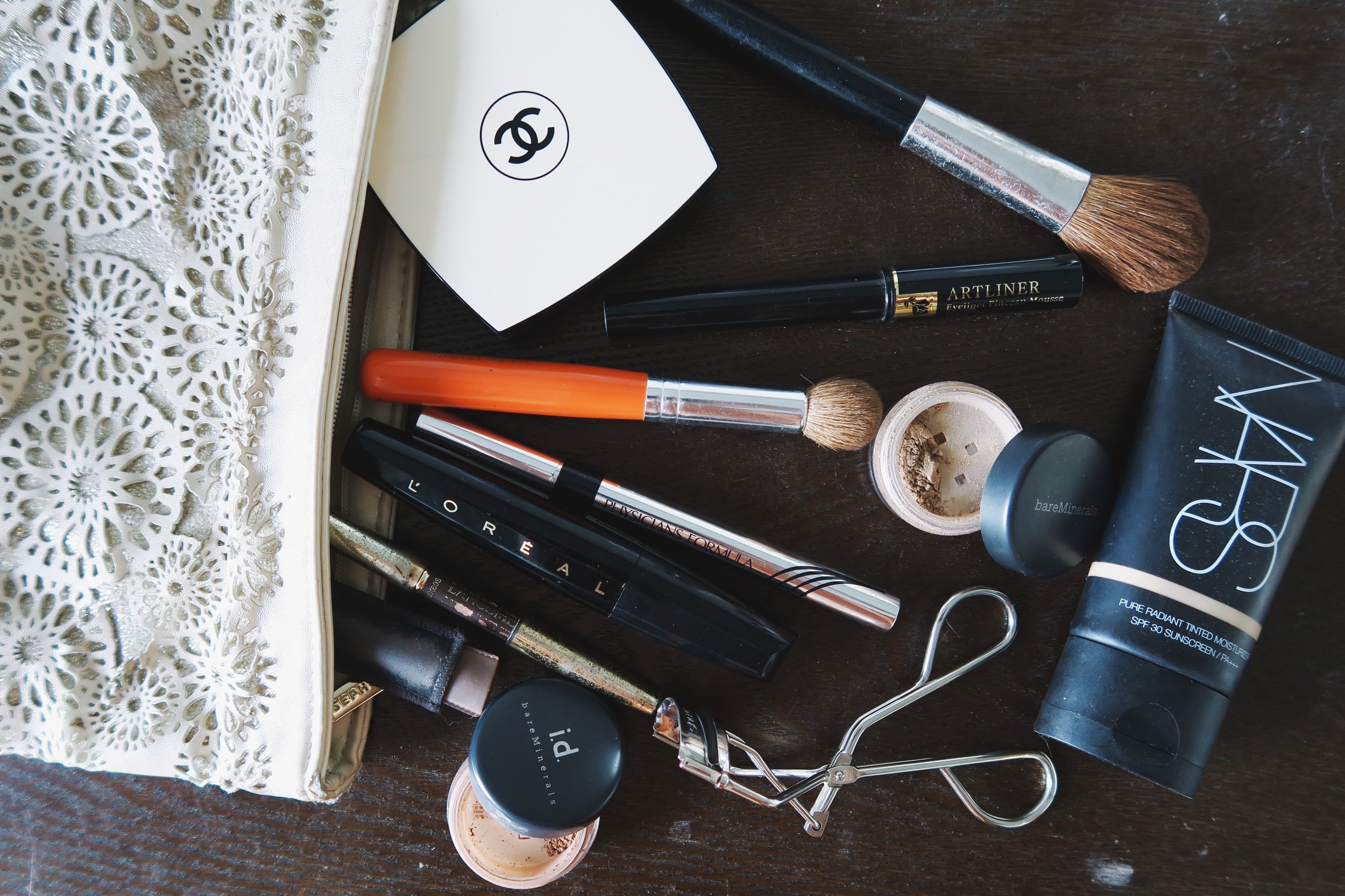 The contents of Maureen's Makeup Bag: Chanel Les Beiges N40, Lancome Artliner, Bare Minerals Shadow in Summer Physician's Formula Eye Liner, L'Oreal Voluminous Mascara, Lancome Le Crayon Poudre in Brunet, Bare Minerals Summer I.D. in Cashmere, …